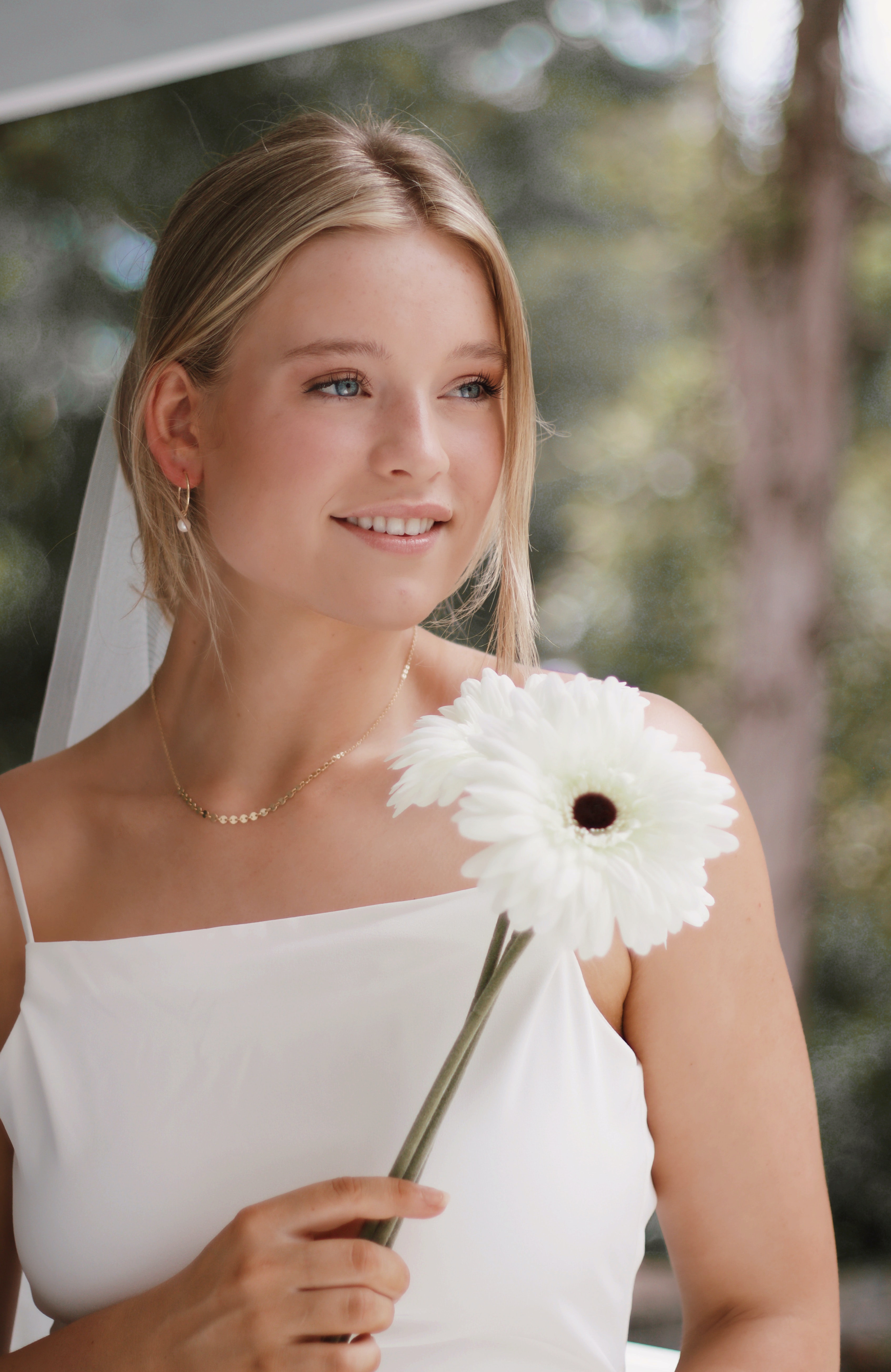 woman in white tube dress holding white flower